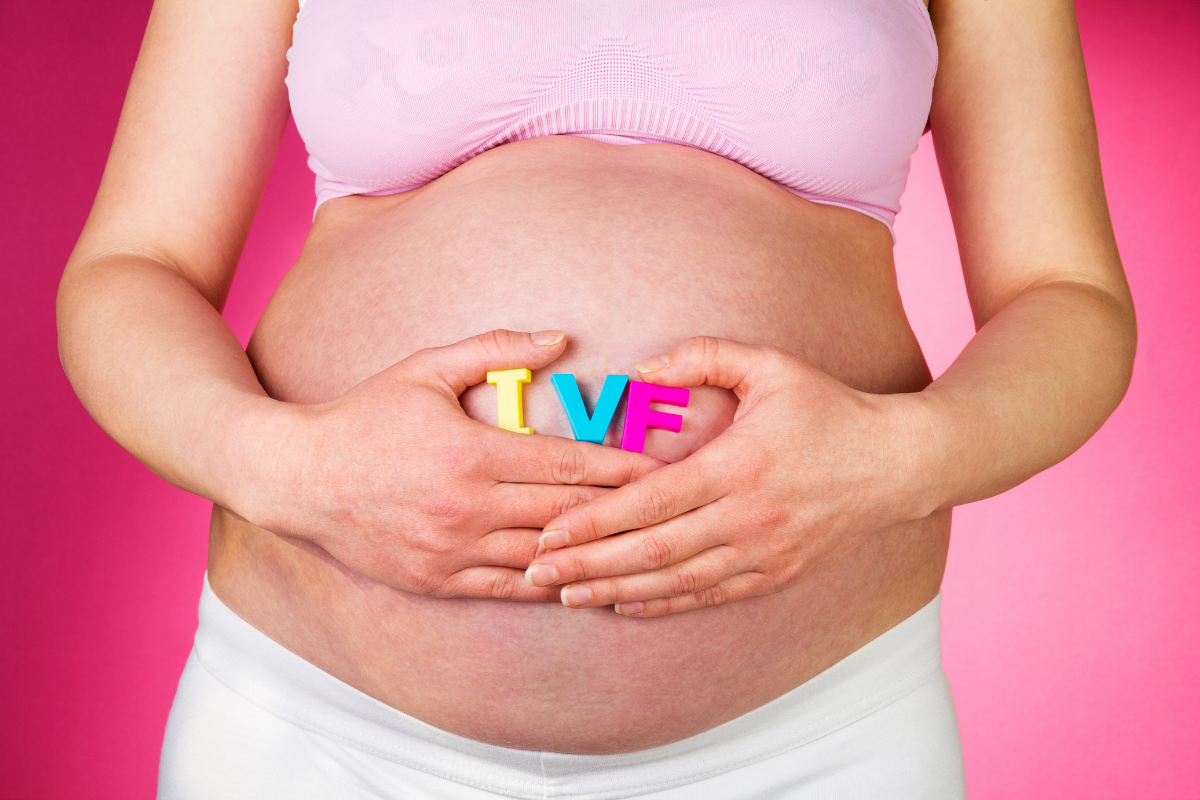 A pregnant woman joyfully holds up the word "love" in colorful letters, symbolizing her anticipation and affection